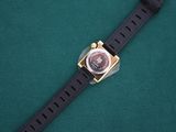 an image of a watch on a green surface with a black strap