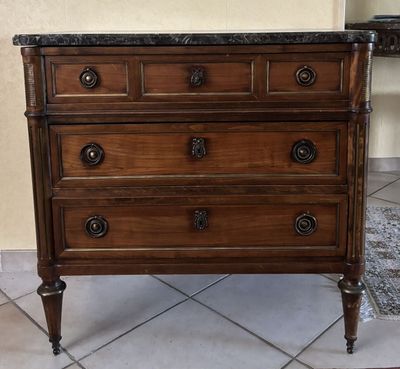 une commode en bois avec un plateau en marbre, posée sur un sol carrelé