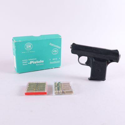 un pistolet et une boîte de cartouches posés sur une surface blanche