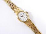 gros plan d'une montre-bracelet en or sur une surface blanche