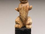 statue d'un singe assis sur un bloc, les mains en l'air