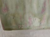 a green vase with pink flowers on it sitting on a table