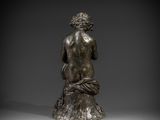 a bronze statue of a woman sitting on a tree stump