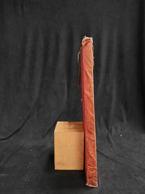 an old red book sitting on top of a wooden block