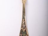 a silver spoon with a gold handle on a white surface