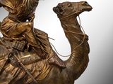 statue en bronze représentant un homme à dos de chameau, avec une selle