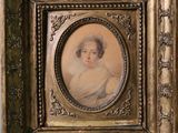 une vieille photo d'une femme en robe blanche dans un cadre doré