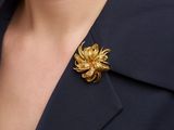 un gros plan sur une femme portant une broche en forme de fleur dorée