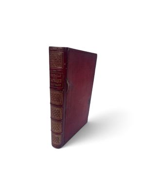 un vieux livre à la couverture rouge posé sur une surface blanche