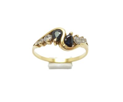 gros plan d'une bague en or avec un saphir et des diamants