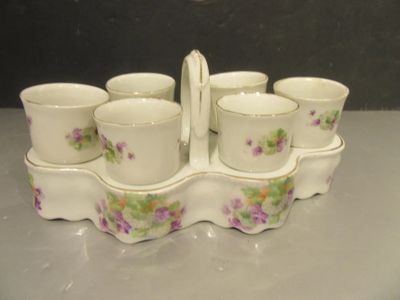 six cups and a tray with a handle on a table