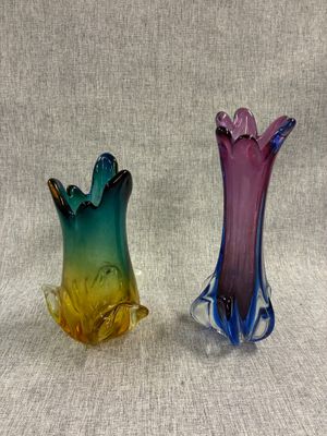 une paire de vases en verre colorés posés l'un à côté de l'autre sur une surface grise