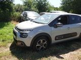 une voiture blanche garée dans un champ, avec d'autres voitures en arrière-plan