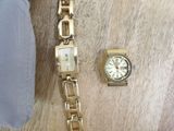 a gold watch and a gold bracelet on a wooden table