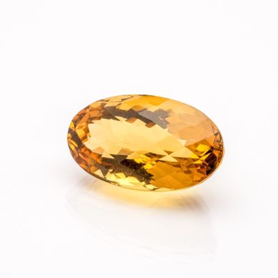 a yellow sapphire stone on a white surface