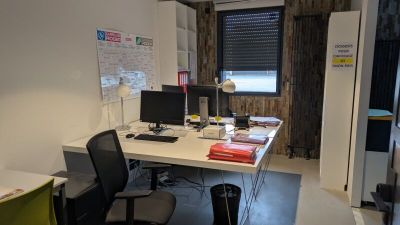 a desk with two computers and a chair in the room