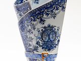 un vase bleu et blanc orné d'une anse dorée sur fond blanc