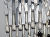 a lot of silver spoons and knives on the table
