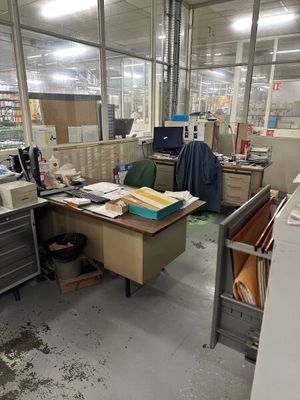 un bureau en désordre, avec beaucoup de bric-à-brac par terre