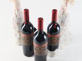 three bottles of red wine sitting next to each other on a white surface