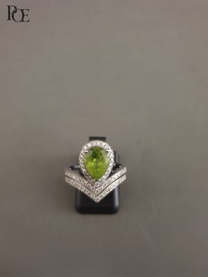 un gros plan d'une bague ornée d'un péridot en forme de cœur entouré de diamants