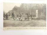 a black and white photo of a group of people on horses and dogs