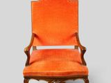 an orange upholstered chair on a grey background