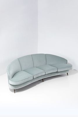 Le canapé incurvé se trouve dans une pièce blanche aux murs blancs.