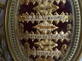 a picture of a gold and red broochle on a white table