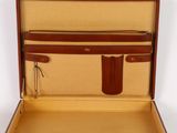 a brown suitcase with a brown handle on a white surface