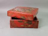 pair of red lacquered boxes with floral designs on them