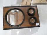 une boîte en bois sur laquelle se trouvent trois bols et une loupe