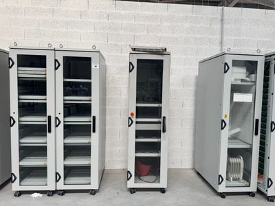 trois armoires de rangement métalliques à portes vitrées dans un entrepôt