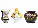 trois vases et une corbeille de fruits posés sur une surface blanche