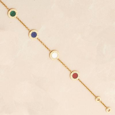 a gold bracelet with multi colored stones on a white background