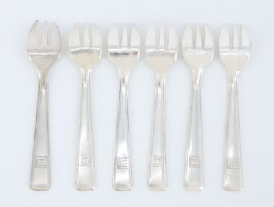 six fourchettes et cuillères sont disposées en ligne sur une surface blanche