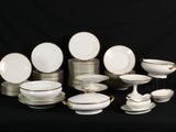 a lot of white and gold plates and bowls on a black background
