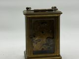 a small brass clock sitting on a white surface