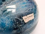 a blue vase with a tag on it on a white surface