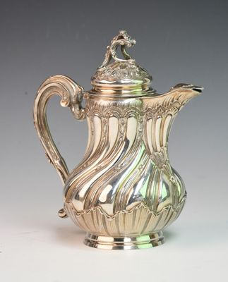 an antique silver coffee pot with a lid on a white surface