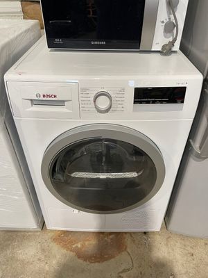 un micro-ondes posé sur une machine à laver, à côté d'un sèche-linge