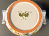 an orange rimmed bowl with a flower design on it