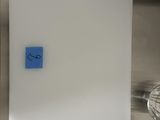 a white board with a blue sticker on it in a kitchen