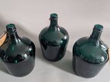three green glass bottles sitting on top of a white table