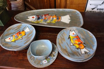 une assiette sur laquelle est peint un poisson, à côté de bols et d'assiettes