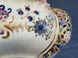a white bowl with flowers on it on a blue surface