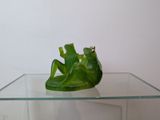 a green frog sitting on top of a glass table