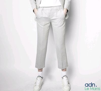 un homme en chemise blanche et pantalon gris qui pose pour une photo