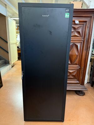 a black refrigerator sitting in a room next to a dresser