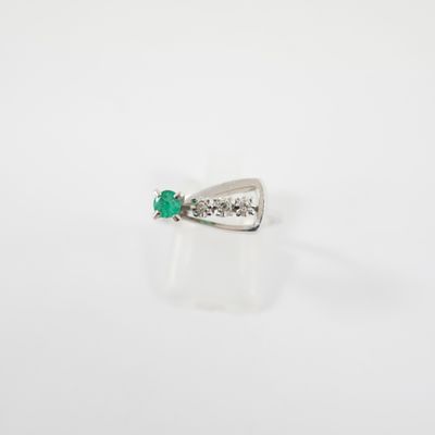une bague en forme de nœud, sertie d'une émeraude et de diamants, sur fond blanc